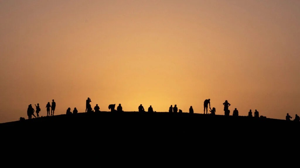 small silhouettes of people against an orange sky